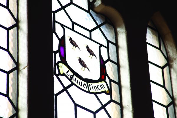 Stained glass window with 3 birds and the school motto Lauda Finem meaning praise till the end
