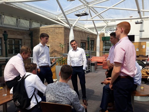 Group of male sixth form students stood talking to male visitor