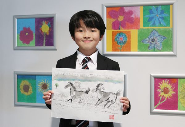 Young boy holding artwork of 3 horses