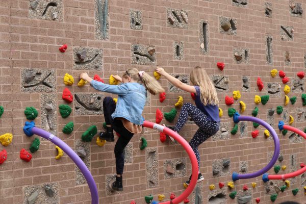 Two girls climbing a climbing wall